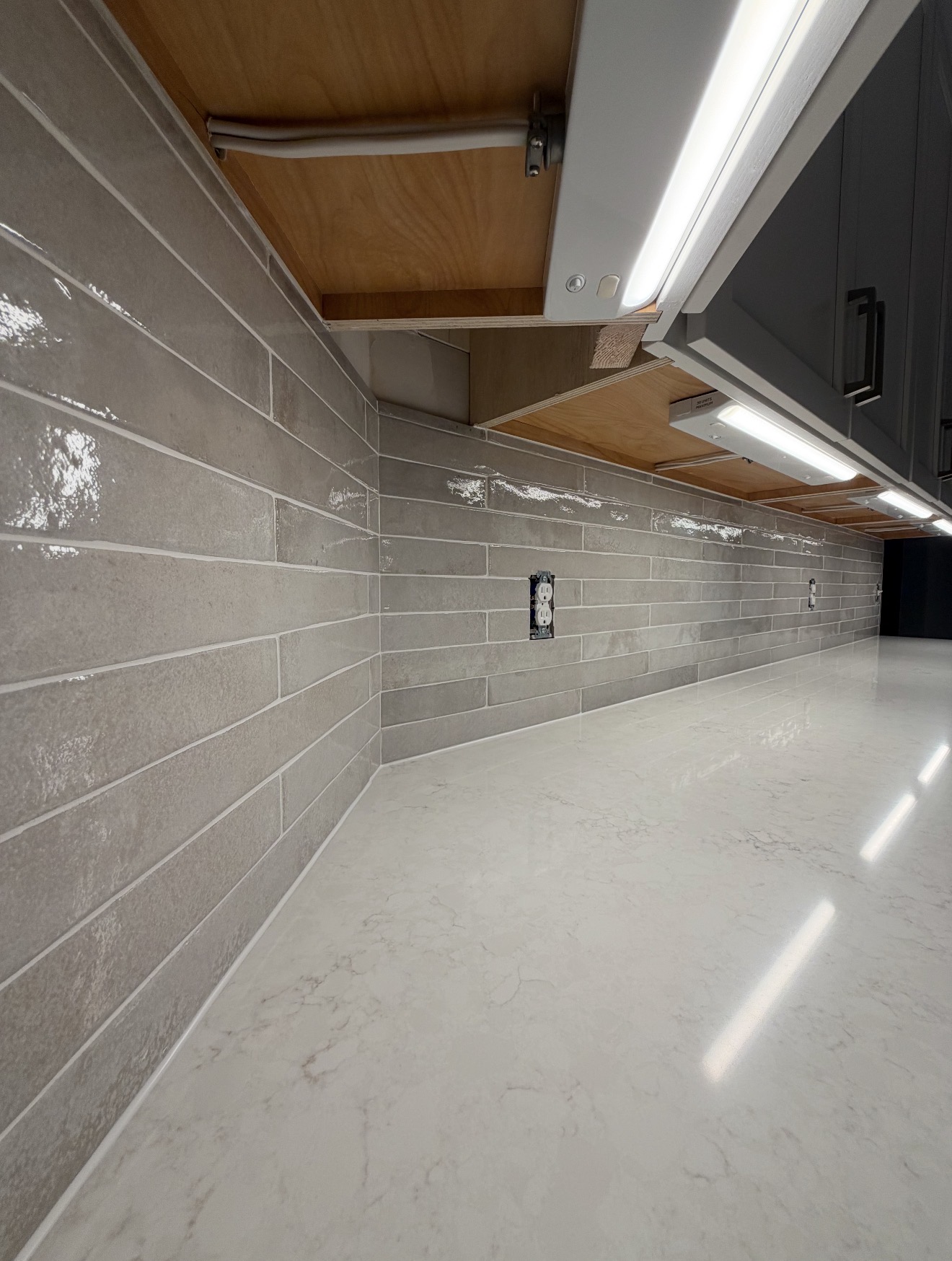 Basement wet-bar kitchenette with gray tile backsplash and quartz counters