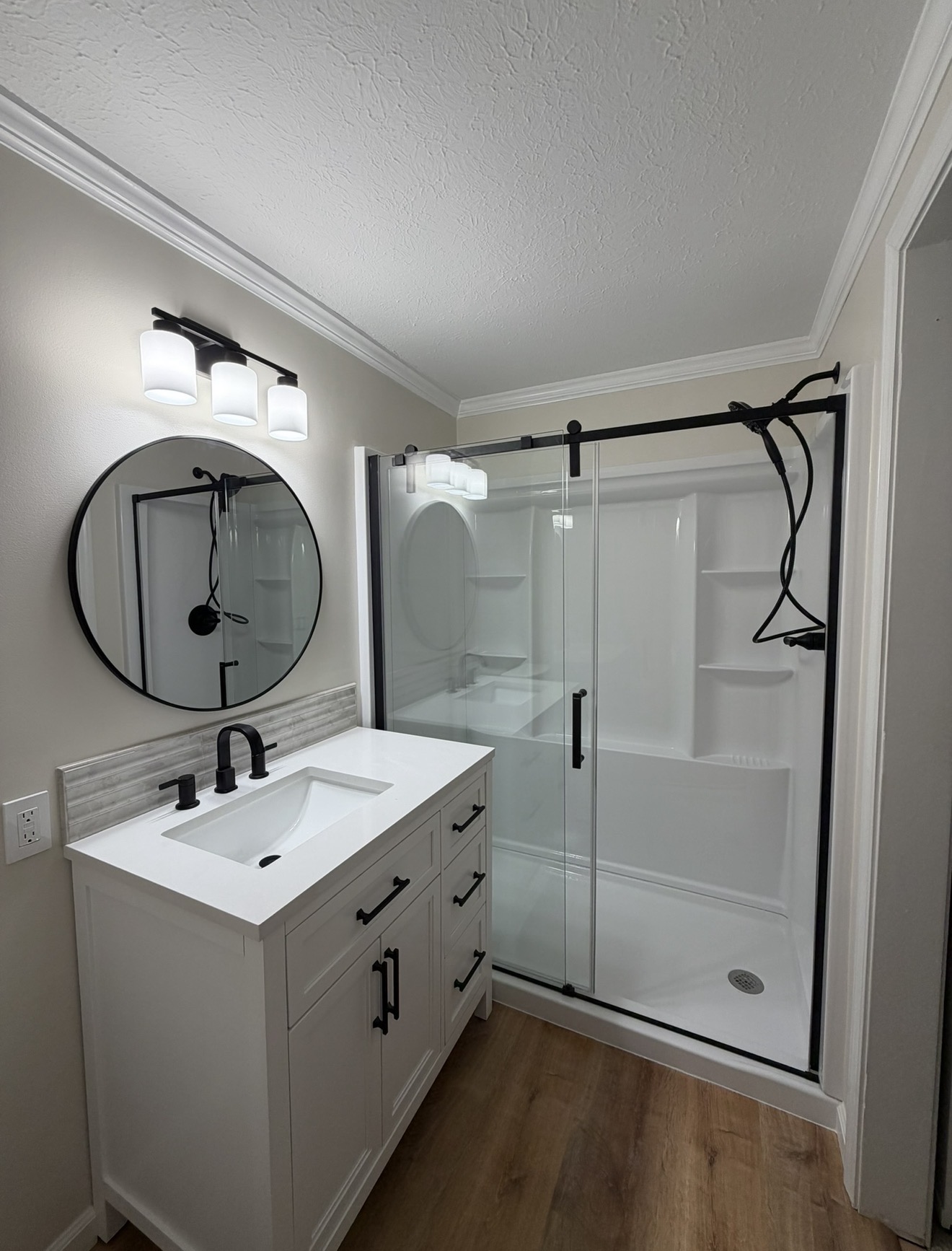 Bathroom remodel with white vanity, black fixtures and glass shower enclosure