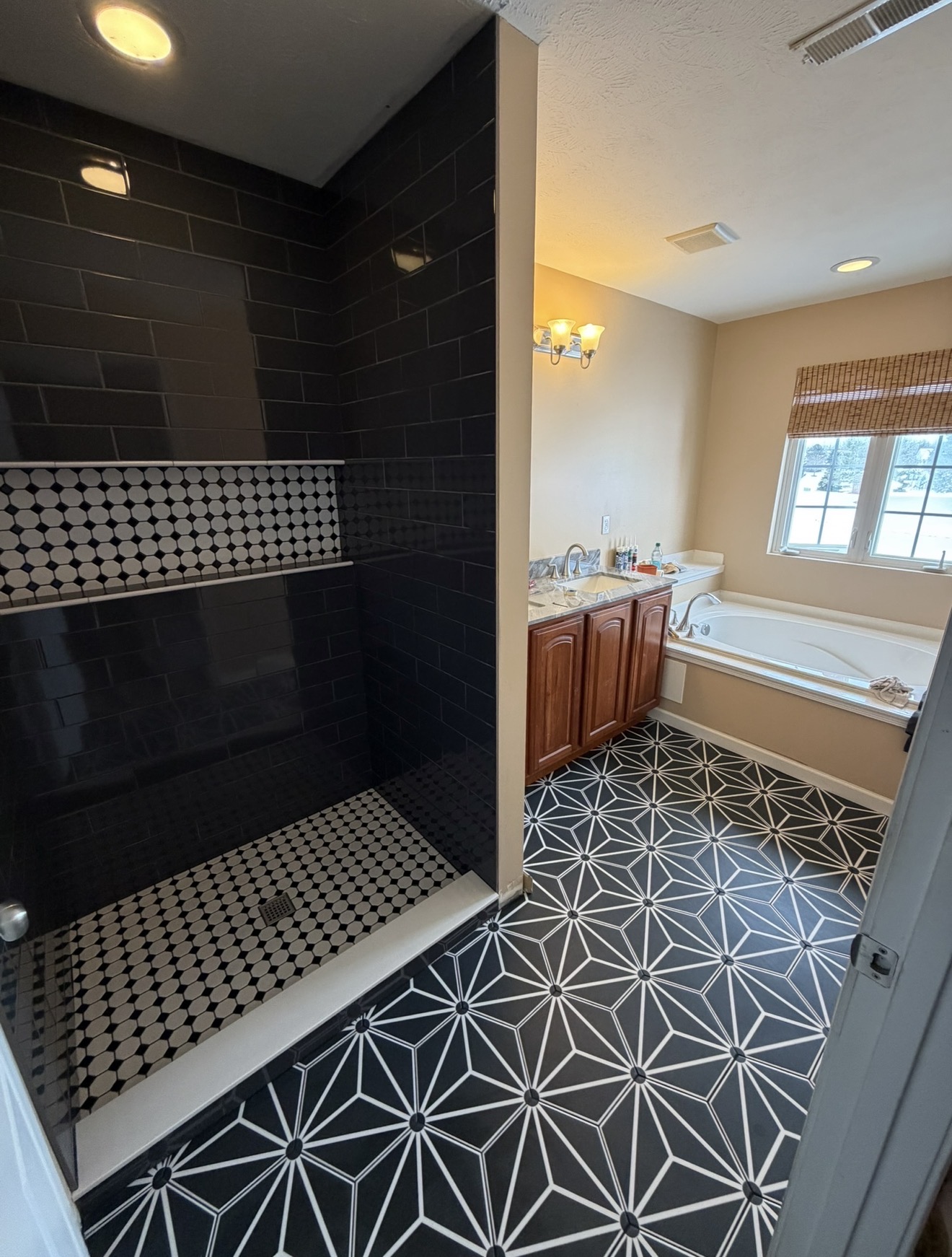 Master bath with black subway tile shower and geometric patterned floor tile