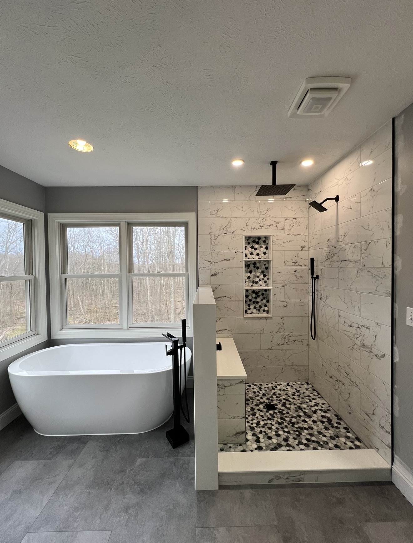 Master bathroom with freestanding soaking tub, marble walk-in shower and pebble tile floor