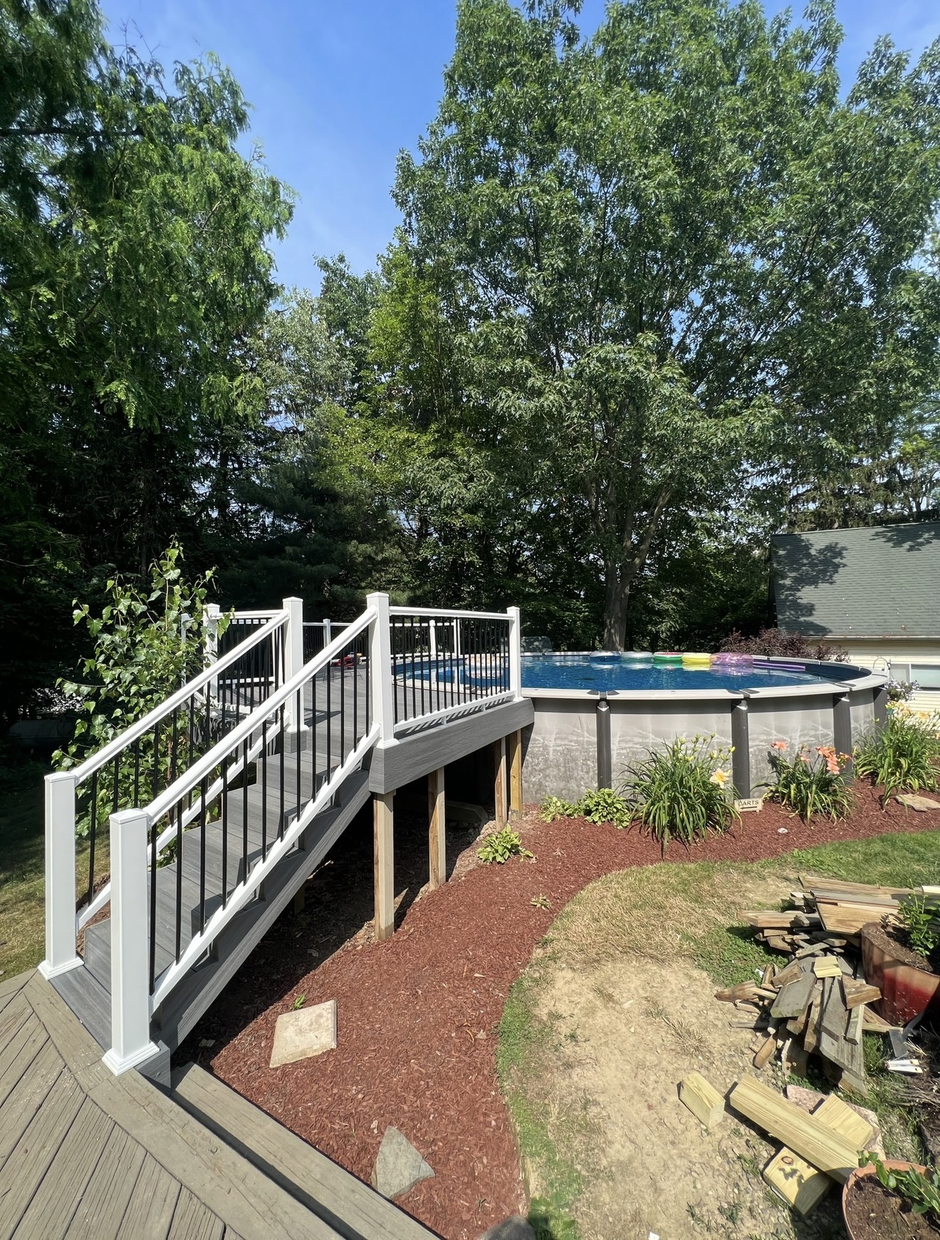 Composite deck with white and black railings, stairs and above-ground pool