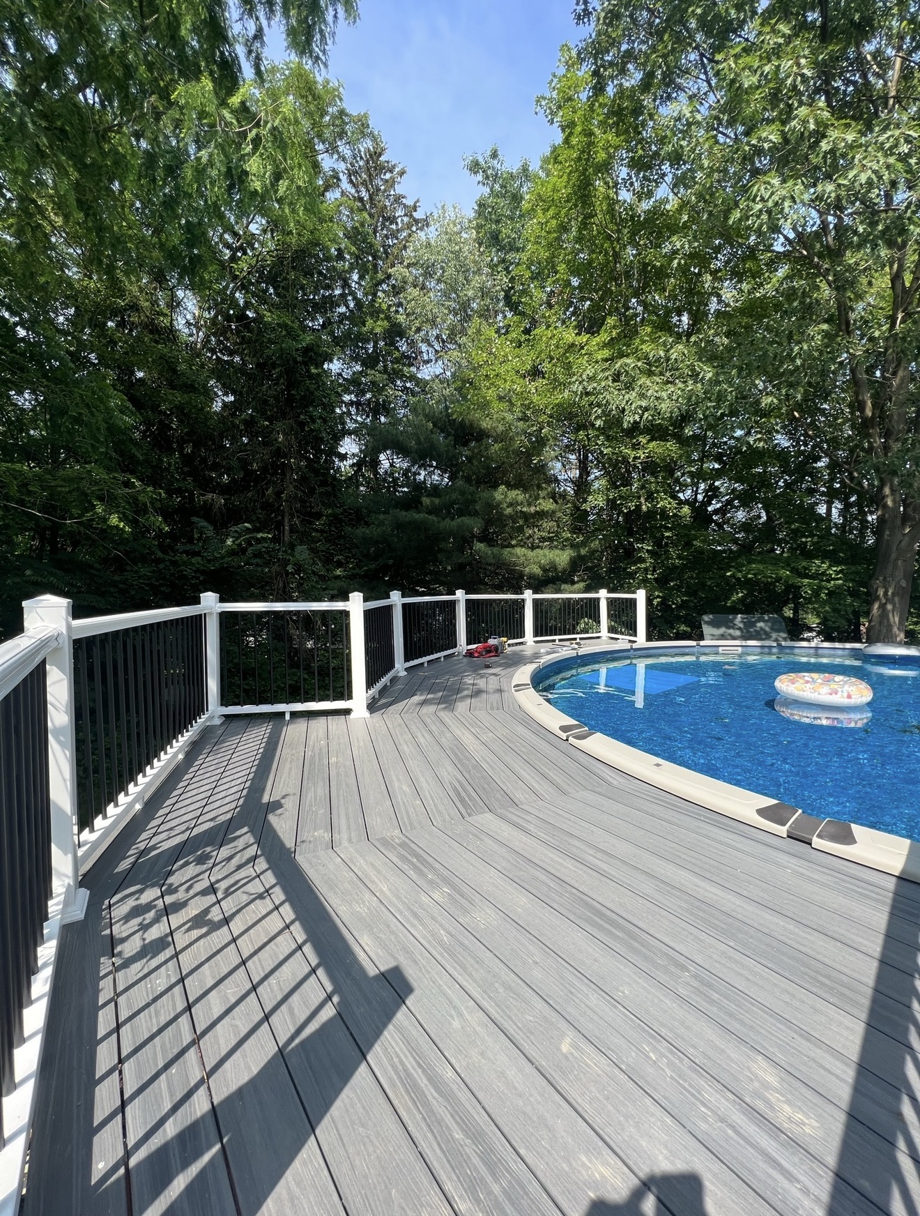Curved composite pool deck with white posts and black aluminum balusters