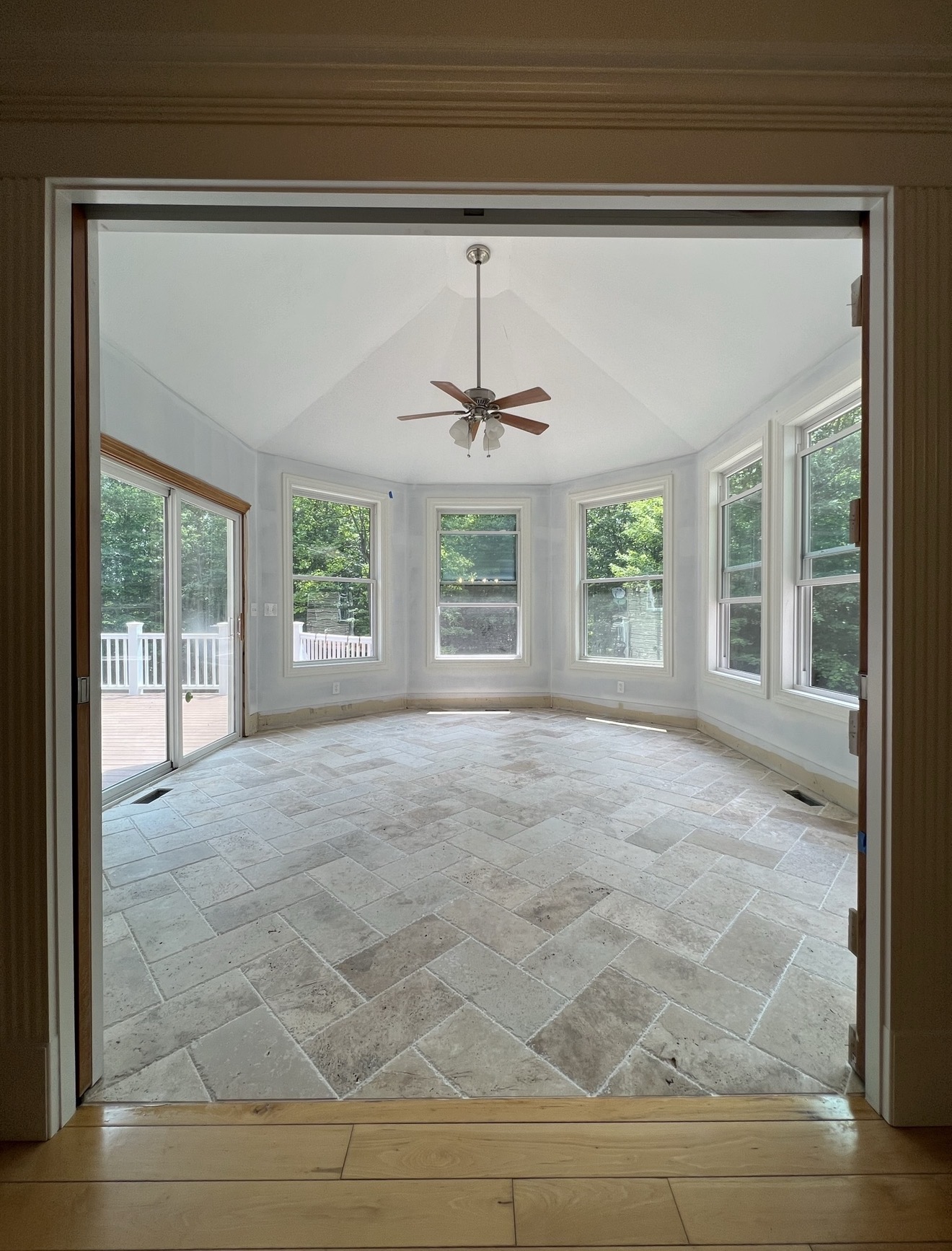 Sunroom addition with vaulted ceiling, ceiling fan and travertine herringbone tile floor