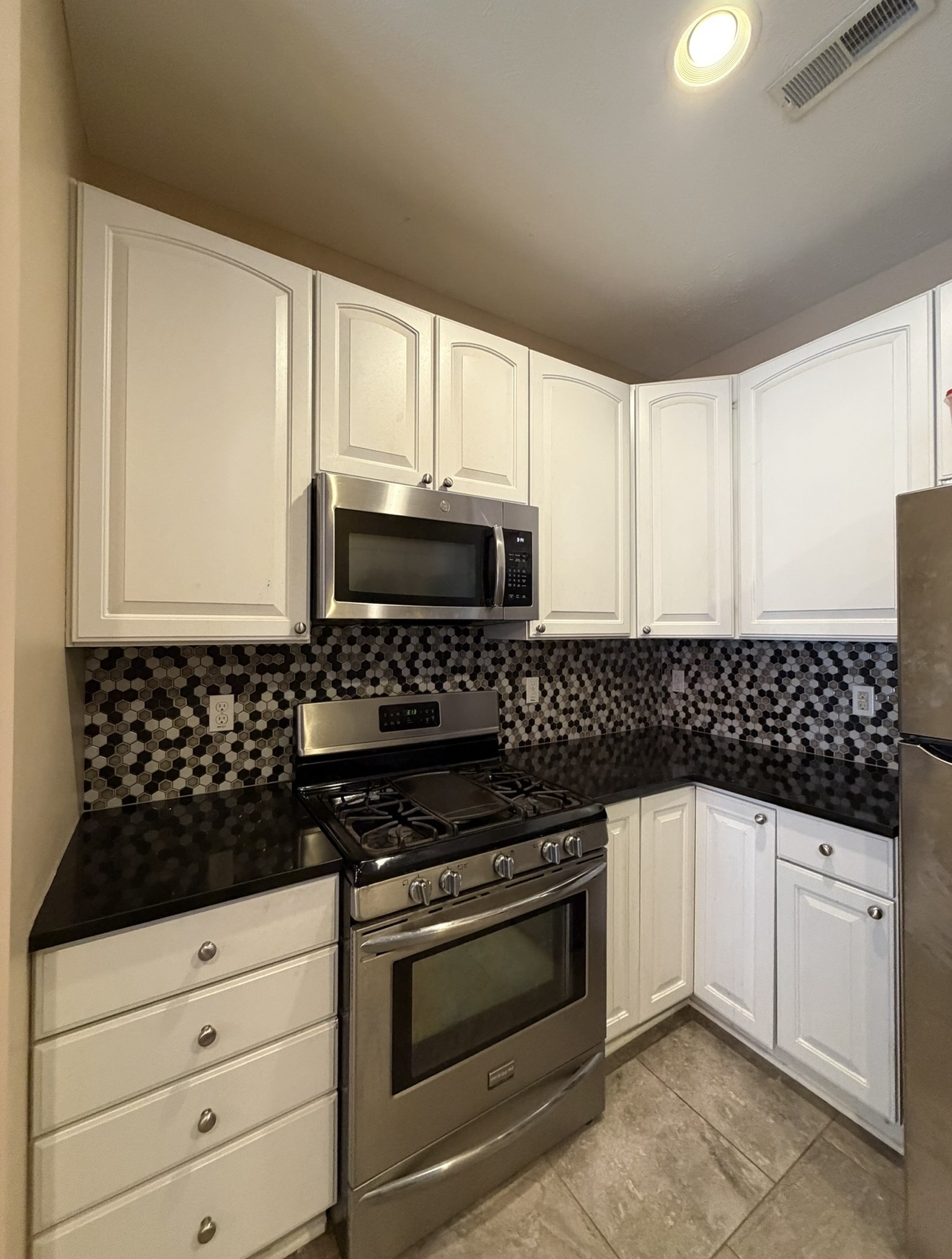 Kitchen remodel with white cabinets, granite counters and hex mosaic backsplash